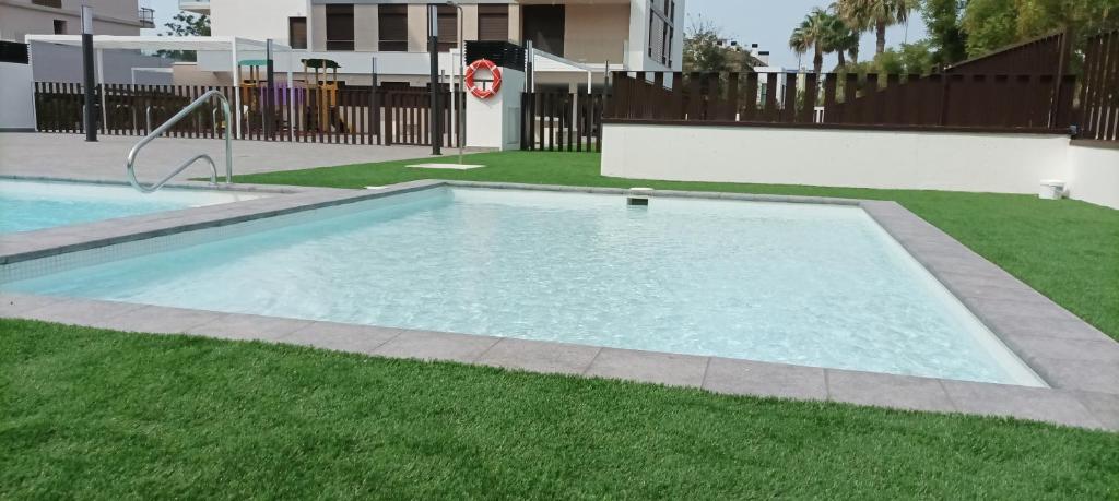 a swimming pool in a yard with green grass at Residencial El Trenet 2C in Benicàssim