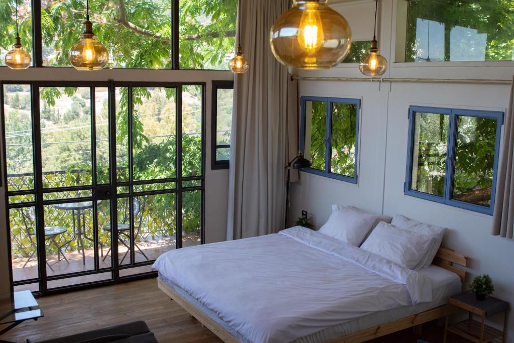 a bedroom with a bed with white sheets and windows at Harmony Inn in Safed