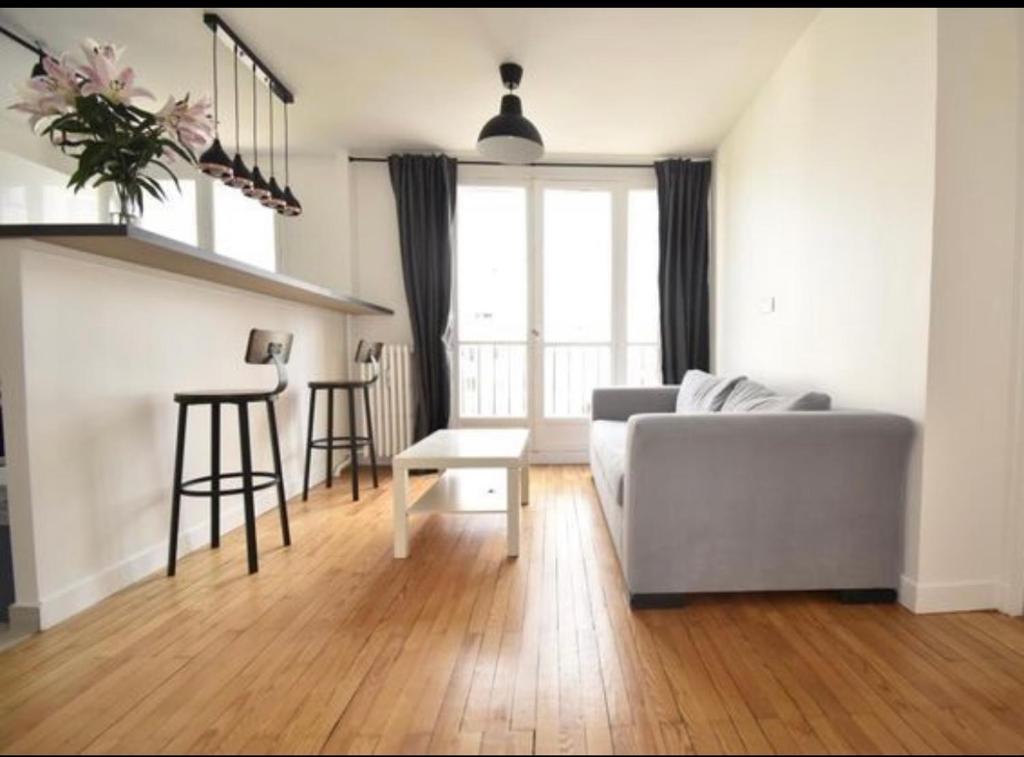 een woonkamer met een bank en een tafel bij Superbe appartement cosy Paris/Stade de France in Aubervilliers