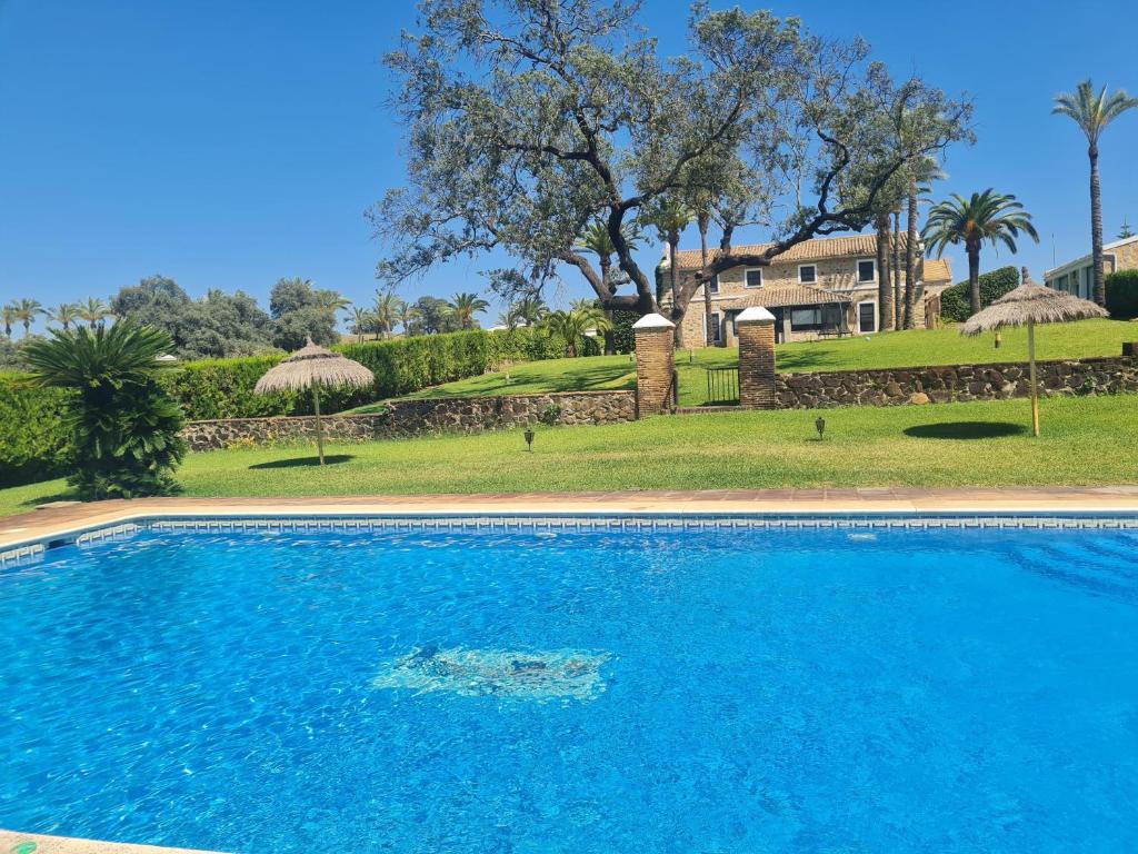 a blue swimming pool in front of a house at Alojamiento Rural Finca Barral in Seville