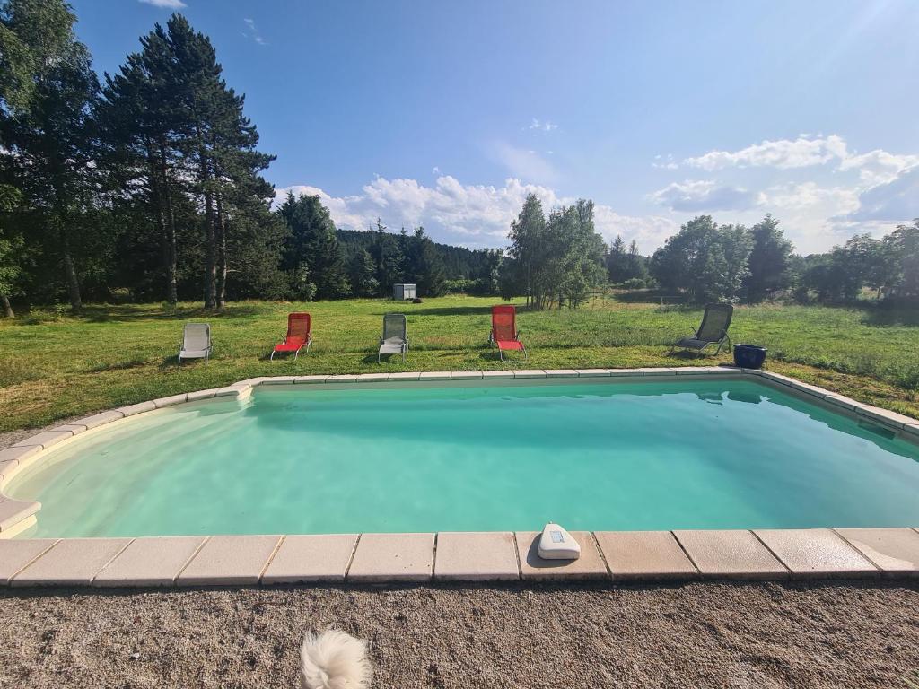 a swimming pool with two chairs at Cosy Room in Saint-Romain-Lachalm