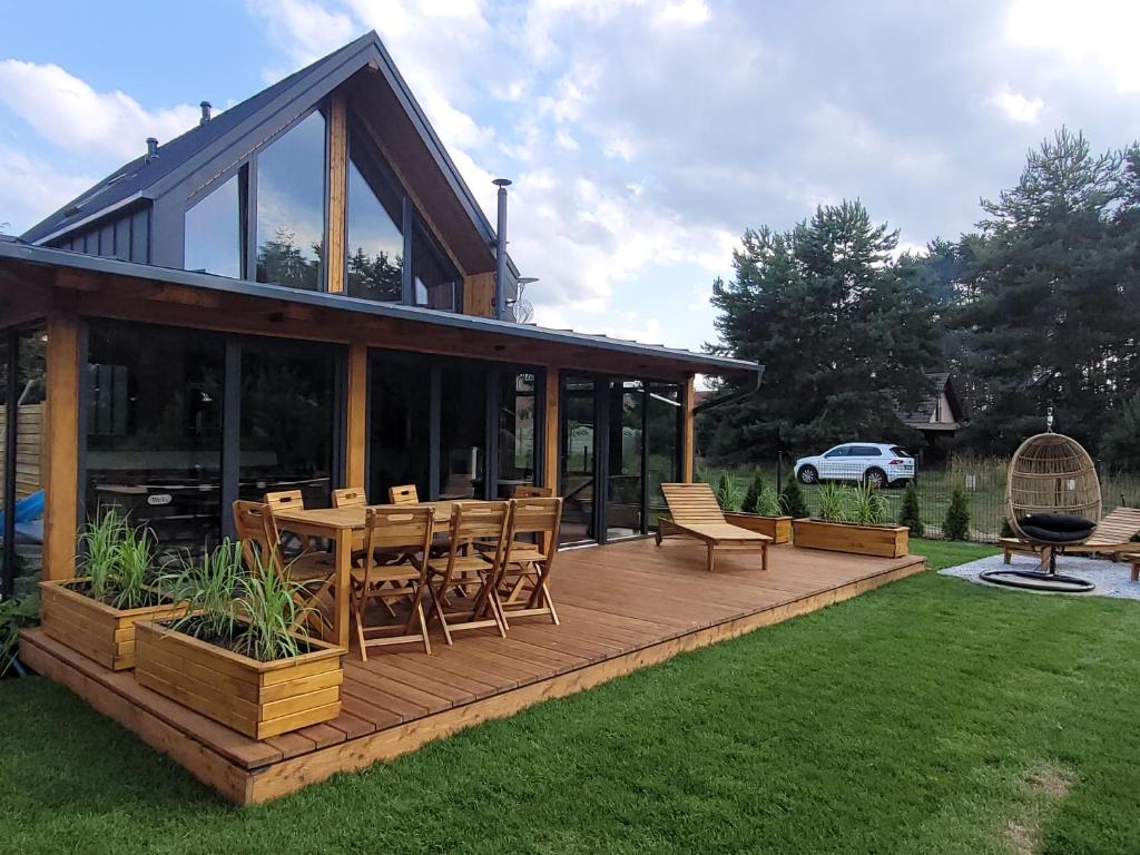 a house with a wooden deck with a table and chairs at LoveLake dom z jacuzzi in Radzyń