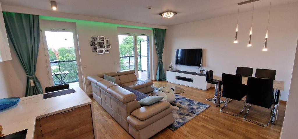 ein Wohnzimmer mit einem Sofa, einem Tisch und einem TV in der Unterkunft River Deluxe Atal Towers Apartment in Breslau