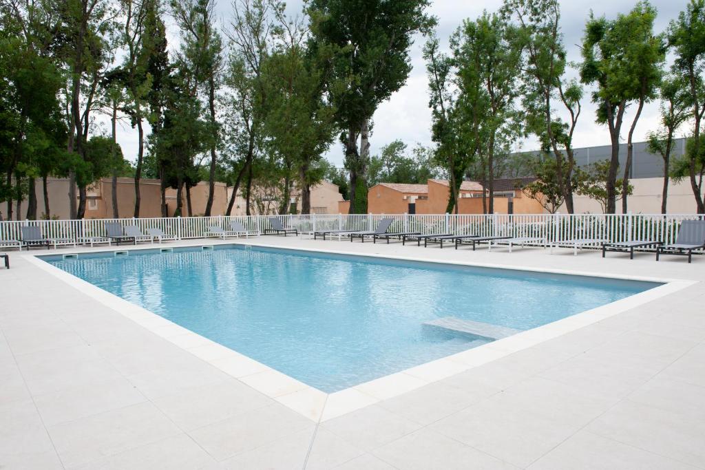 een groot zwembad met stoelen en bomen bij Le bastidon de Stéphanie Saint Rémy de Provence in Saint-Rémy-de-Provence