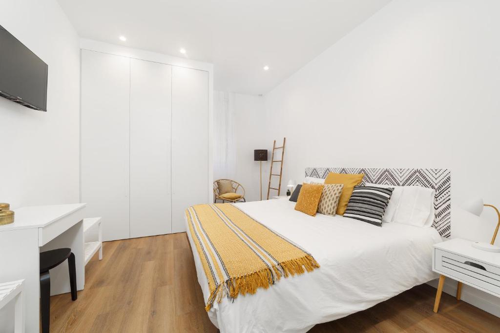 a white bedroom with a bed and a desk at LUMO Flat Fátima in Fátima