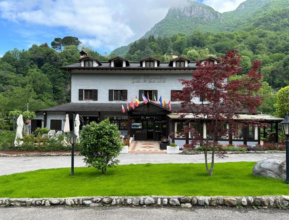 a large white building with mountains in the background at Hotel Al Verde in Mandello del Lario