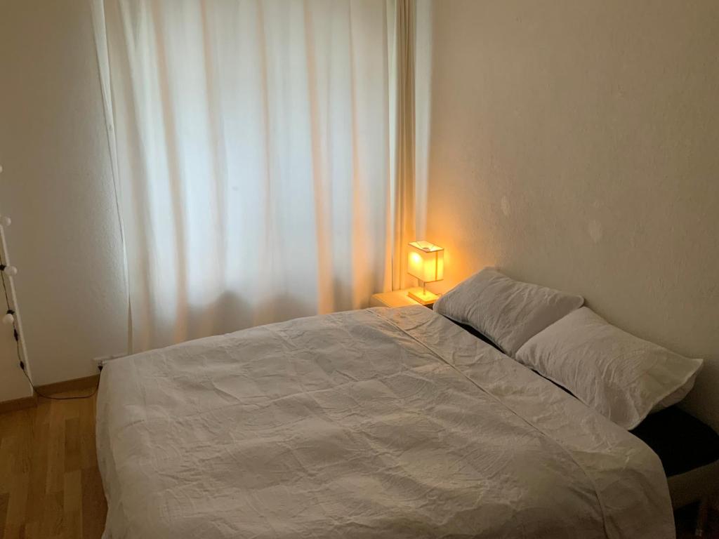 a white bed in a bedroom with a lamp at Lion BB Swiss in Zurich
