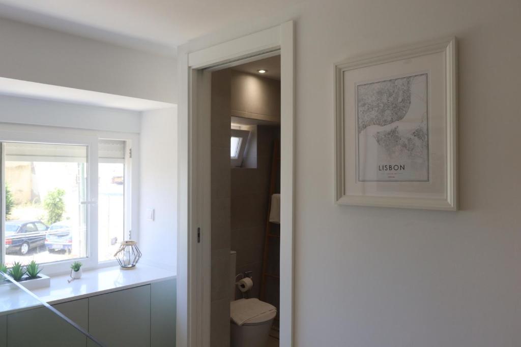 a bathroom with a toilet and a picture on the wall at Lisbon, T2 renewed duplex with river view, Beato, Lisbon in Lisbon