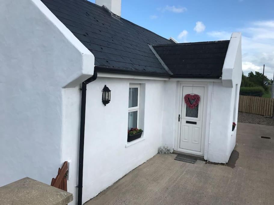 a white house with a door and a wreath on it at Cosy Nook Cottage Kesh in Kesh