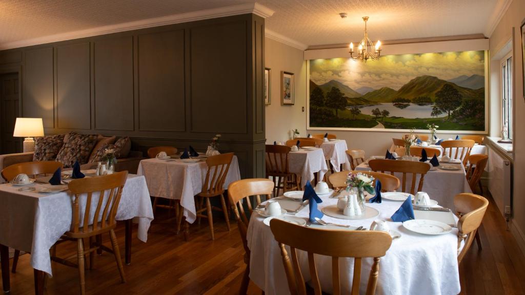 um restaurante com mesas e cadeiras brancas e um quadro em Adare Guesthouse em Galway