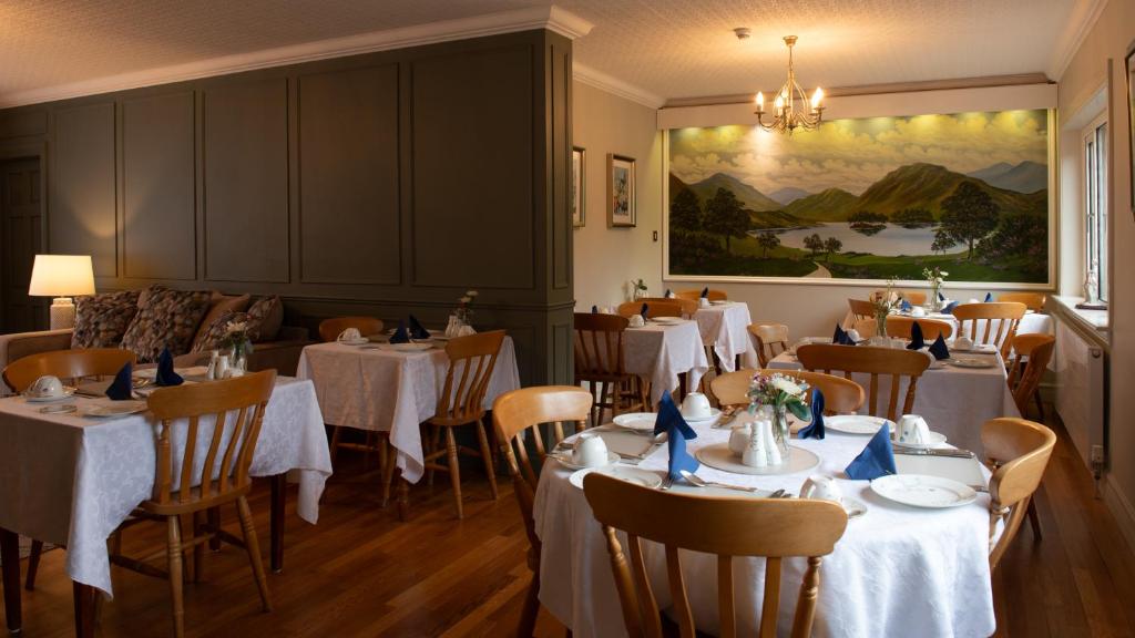 un restaurante con mesas y sillas blancas y una pintura en Adare Guesthouse, en Galway