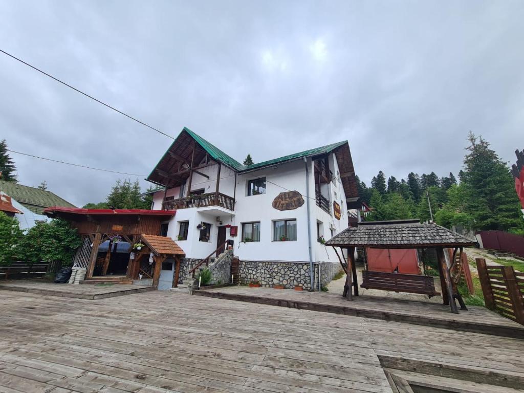 un grand bâtiment blanc avec un banc devant lui dans l'établissement Vila Vitalis, à Predeal