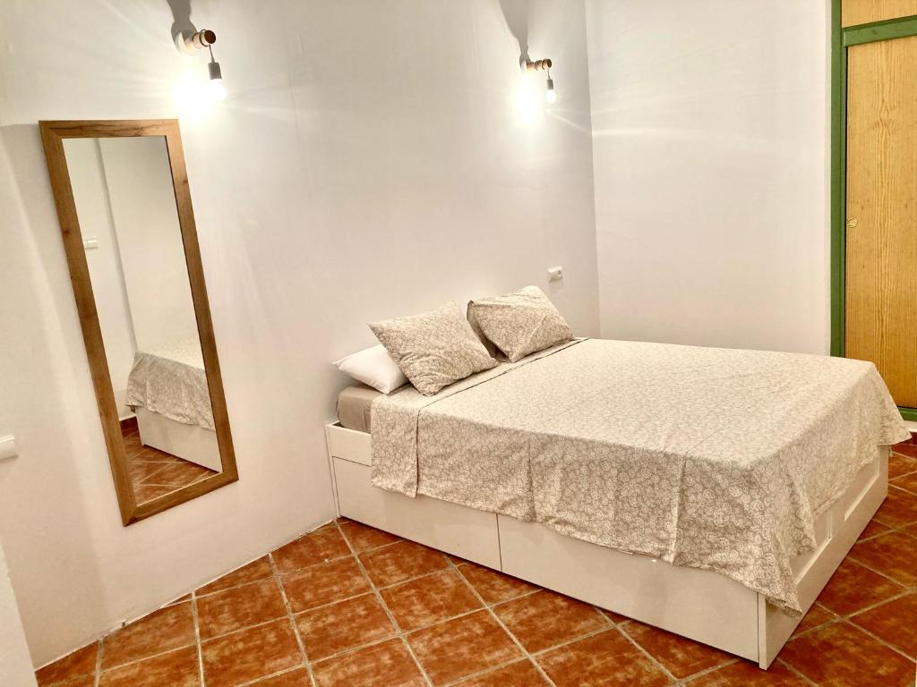 a small bedroom with a bed and a mirror at Casa rural Almazara in Letur