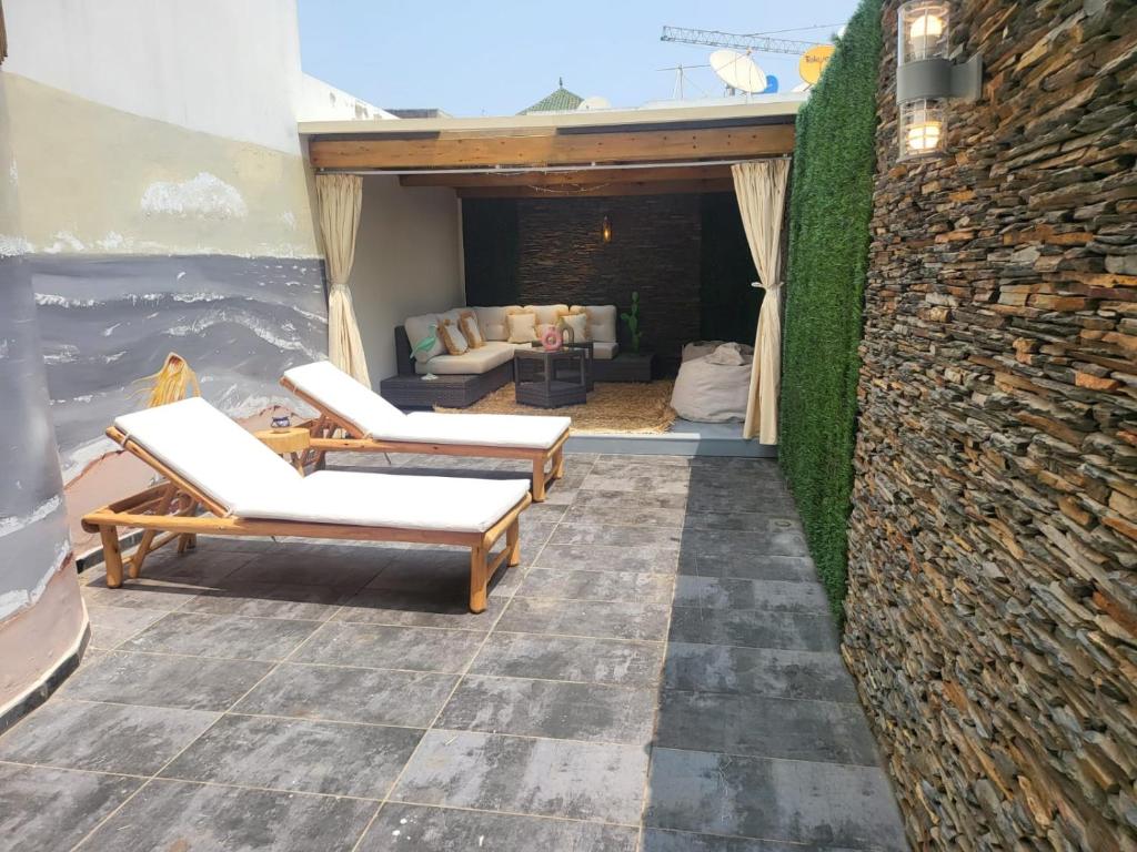 a patio with two lounge chairs and a stone wall at L'Amouage Casablanca Location Journalière Casablanca in Casablanca