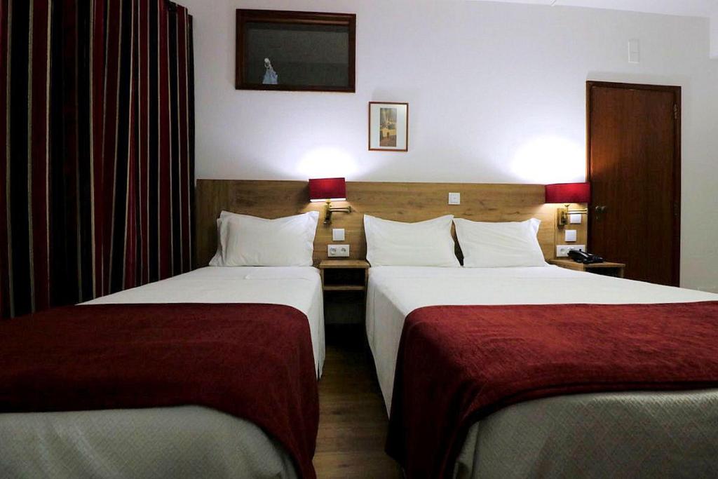 Cette chambre d'hôtel comprend 2 lits avec des draps rouges. dans l'établissement Hotel Rota Malhoa, à Figueiró dos Vinhos