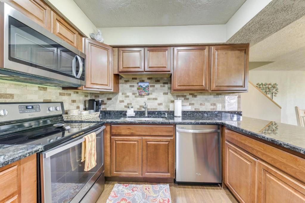 a kitchen with wooden cabinets and stainless steel appliances at Ruidoso Golf Condo - Patio, Fire Pit and Mtn View! in Ruidoso