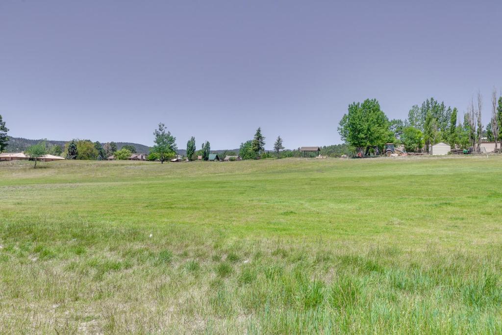 a large field of grass with trees in the background at Ruidoso Golf Condo - Patio, Fire Pit and Mtn View! in Ruidoso