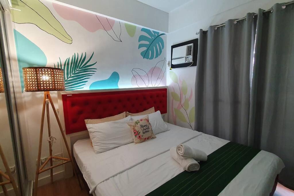 a bedroom with a bed with a red headboard at Tropical Escape at Cedar Crest in Manila