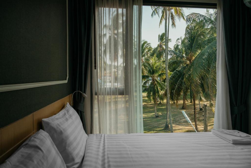 a bedroom with a bed and a window with palm trees at Phuket, Surin beach in Surin Beach
