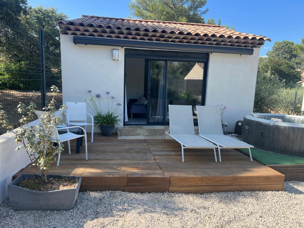 a wooden deck with white chairs and a house at Maisonnette 32m2 climatisé avec jacuzzi au calme. in Trans-en-Provence