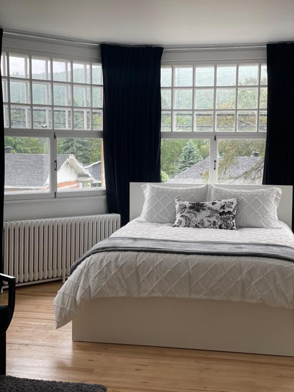 a bedroom with a bed and a large window at Hôtel Le Rustique in Saint-Irénée