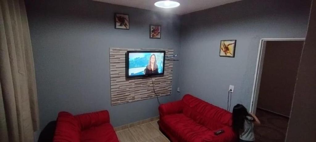 a living room with a red couch and a flat screen tv at Casa de Boneca aconchegante in Uberaba