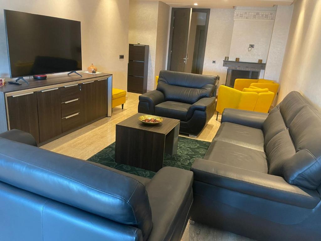 a living room with a couch and chairs and a flat screen tv at APPARTEMENT HAUT STANDING proche gare casa voyageur in Casablanca