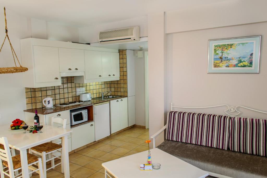 a small kitchen with white cabinets and a table at Aktea Beach Village in Ayia Napa