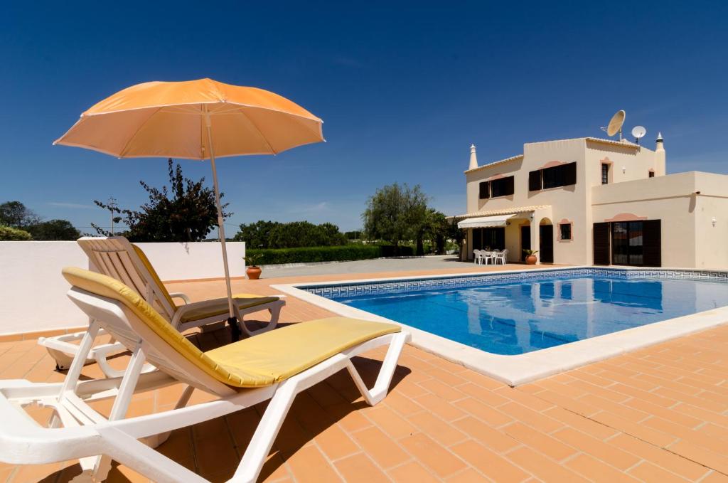 a chair and an umbrella next to a swimming pool at Villa Eucalipto in Lagoa