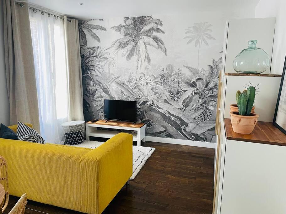 a living room with a yellow couch and a wall mural at Comme à la maison-Porte de Paris in Pantin