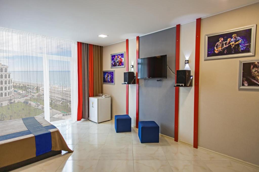 a bedroom with a bed and a tv and a window at Sea View Rock Hotel in Batumi