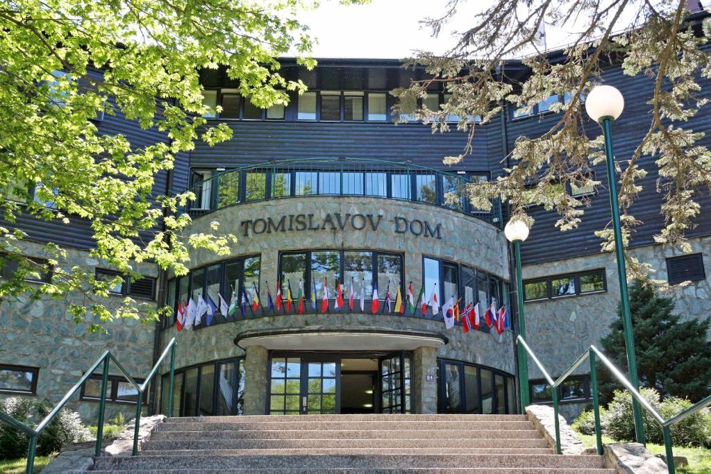 a building with a staircase in front of a building with flags at Hotel Tomislavov Dom in Zagreb