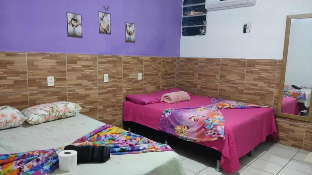 2 camas en una habitación con paredes moradas en Pousada Carimbó, en Fortaleza