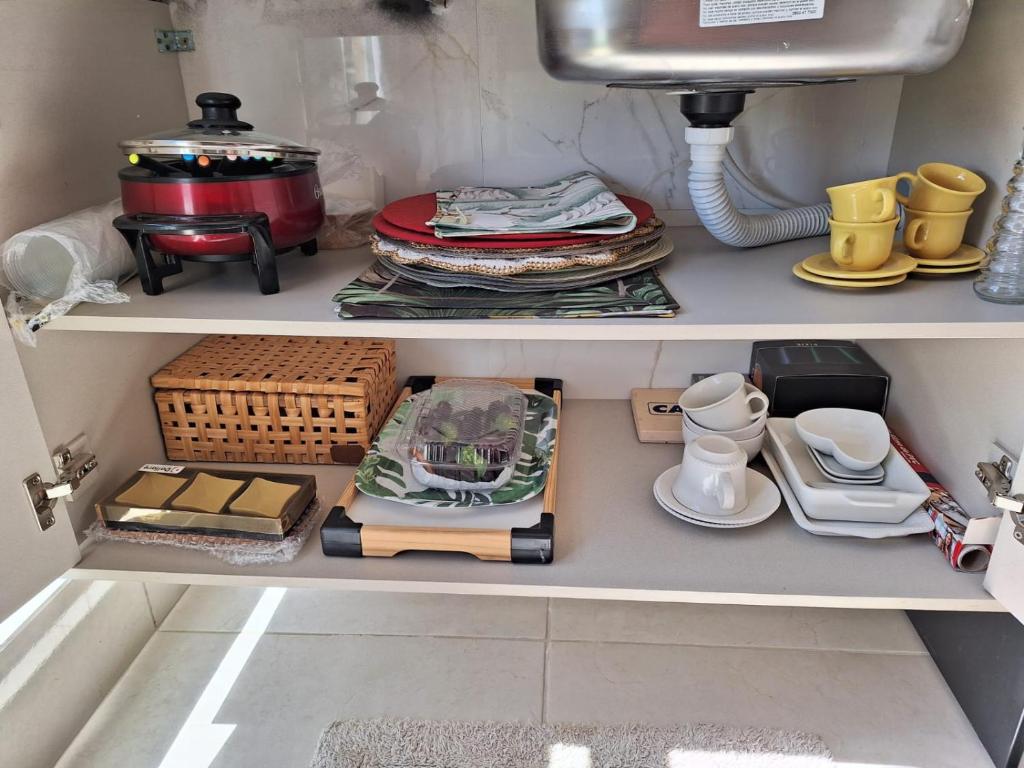 a cupboard filled with dishes and other kitchen items at Aconchegante apartamento studio em Bananeiras in Bananeiras
