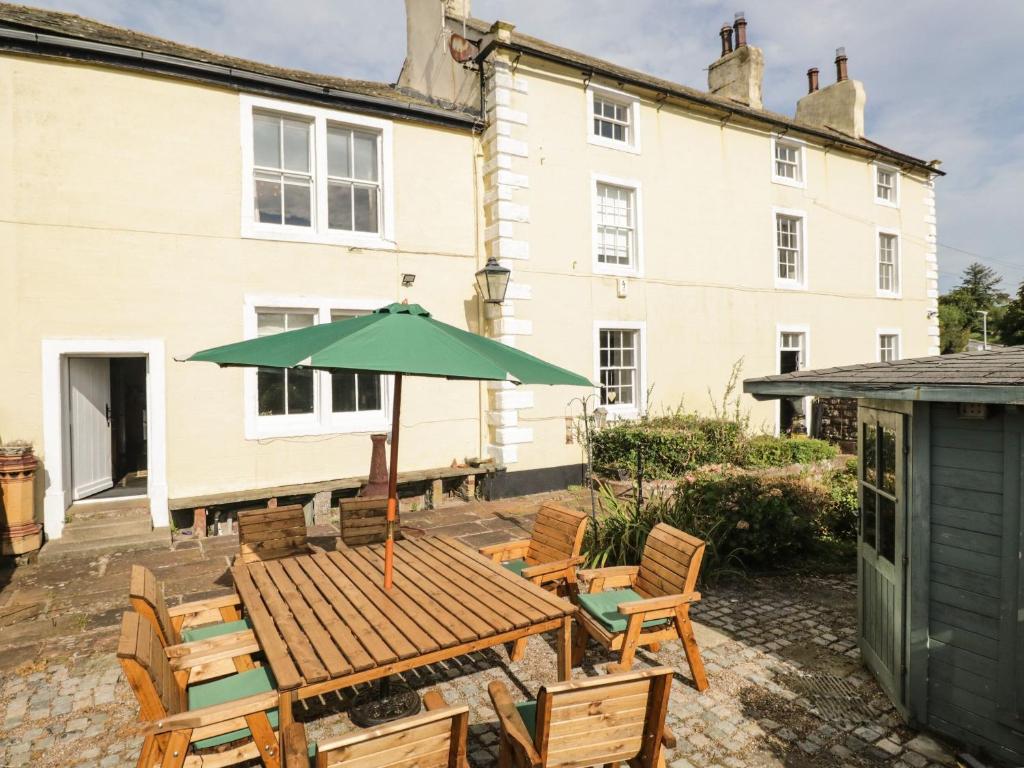 a patio with a wooden table and chairs and an umbrella at Abbey Farm House in St Bees