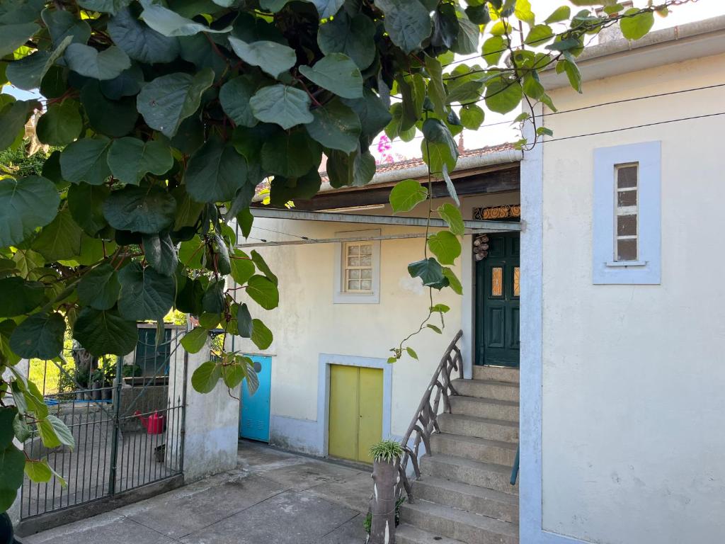 a white house with a yellow door and stairs at Casa do Sete in Vilar do Pinheiro