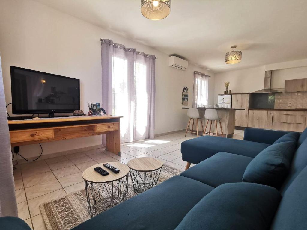 a living room with a blue couch and a tv at Maison O Volets Bleus Calme Jardin in Miramas