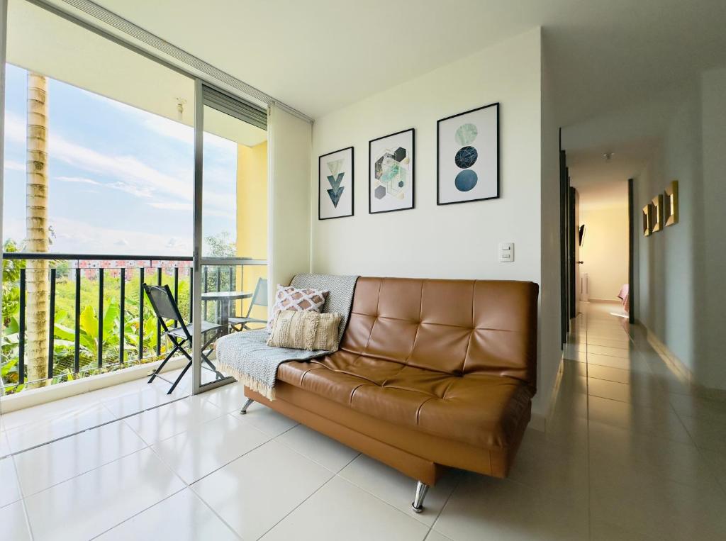 a brown leather couch in a living room with a balcony at Full furnished apartment in Pereira in Pereira