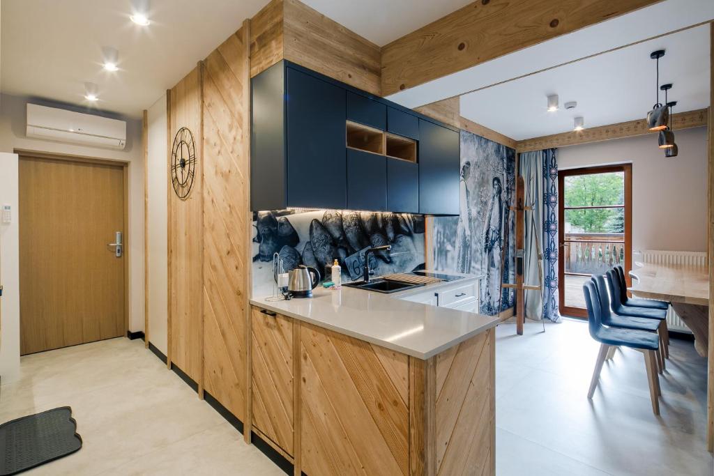 cocina con paredes de madera y armarios azules en Górskie Szczyty Apart & SPA Apartament 11 Sauna Jacuzzi i Parking w cenie en Zakopane