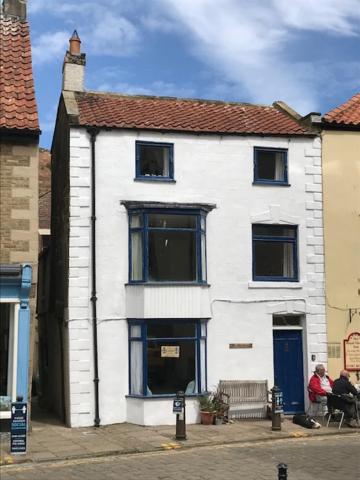 a white house with people sitting in front of it at The Anchorage your home in idyllic Staithes in Staithes