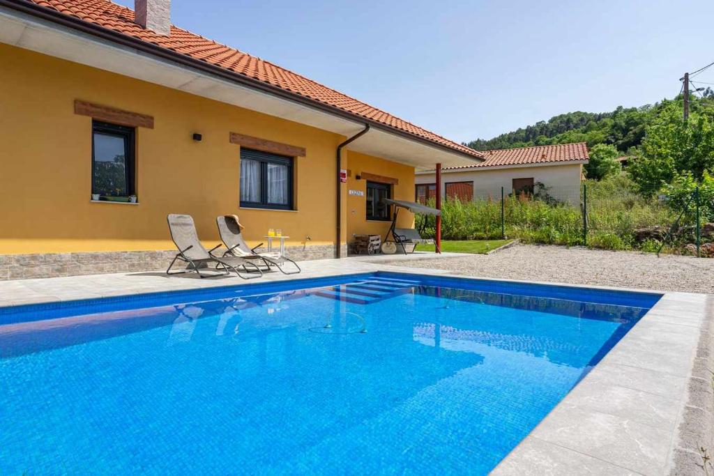 una piscina con 2 sillas junto a una casa en Casa Rural en Lucena, en Arboleya