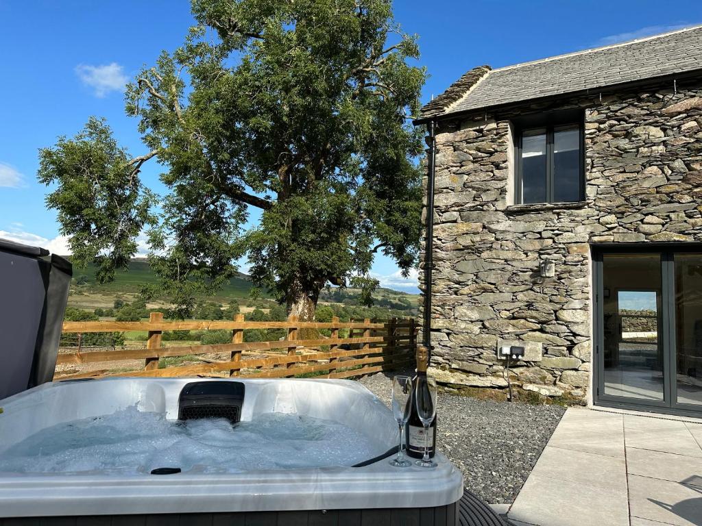 a bath tub in front of a stone building at Meadow Syke Byre in Penrith