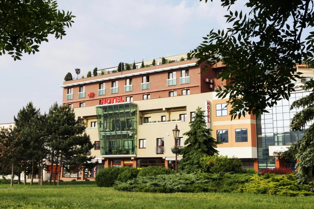 a building with a glass facade in a park at City Hotel Nitra in Nitra