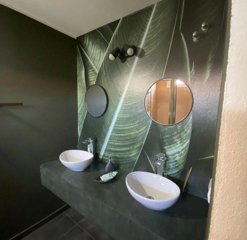 Baño con 2 lavabos y espejo en Cañas Suites Villa Cura Brochero en Villa Cura Brochero