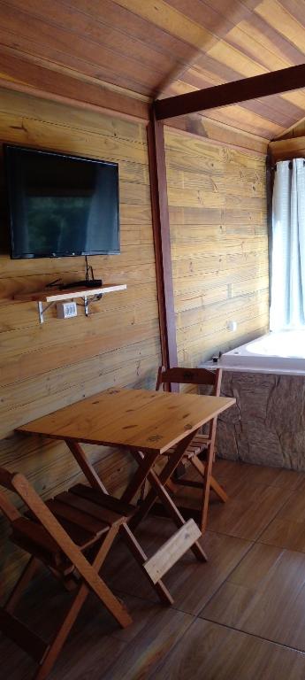 a wooden table and chair in a room with a bed at Chale brilho do sol in Visconde De Maua