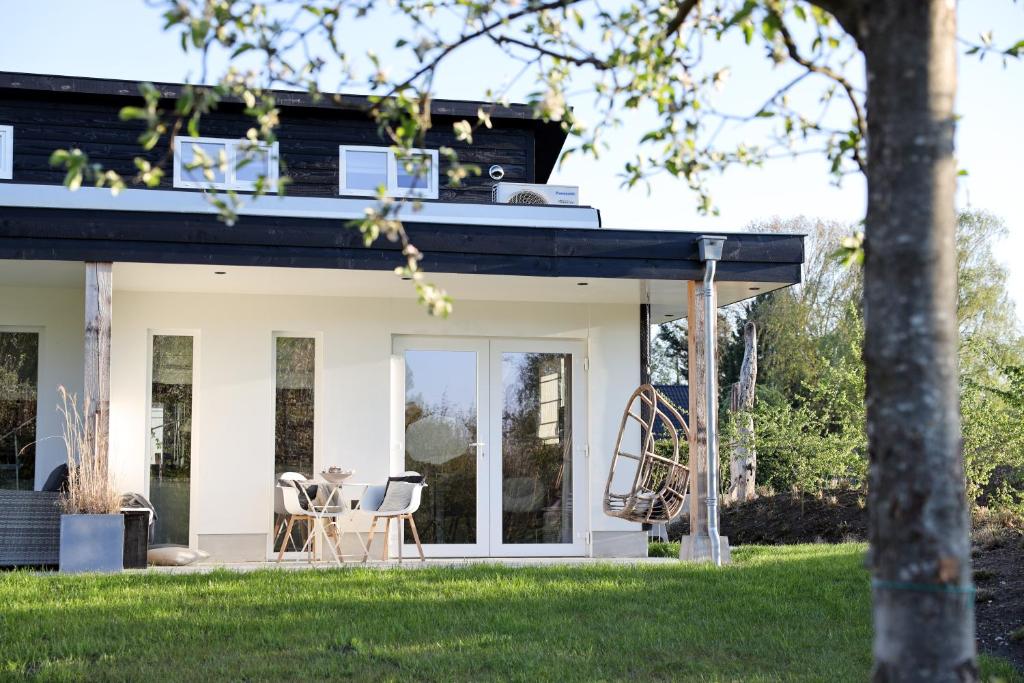 een wit huis met een zwart dak en stoelen bij Stijlvol huisje met veranda! Tuynloodz A in Beers