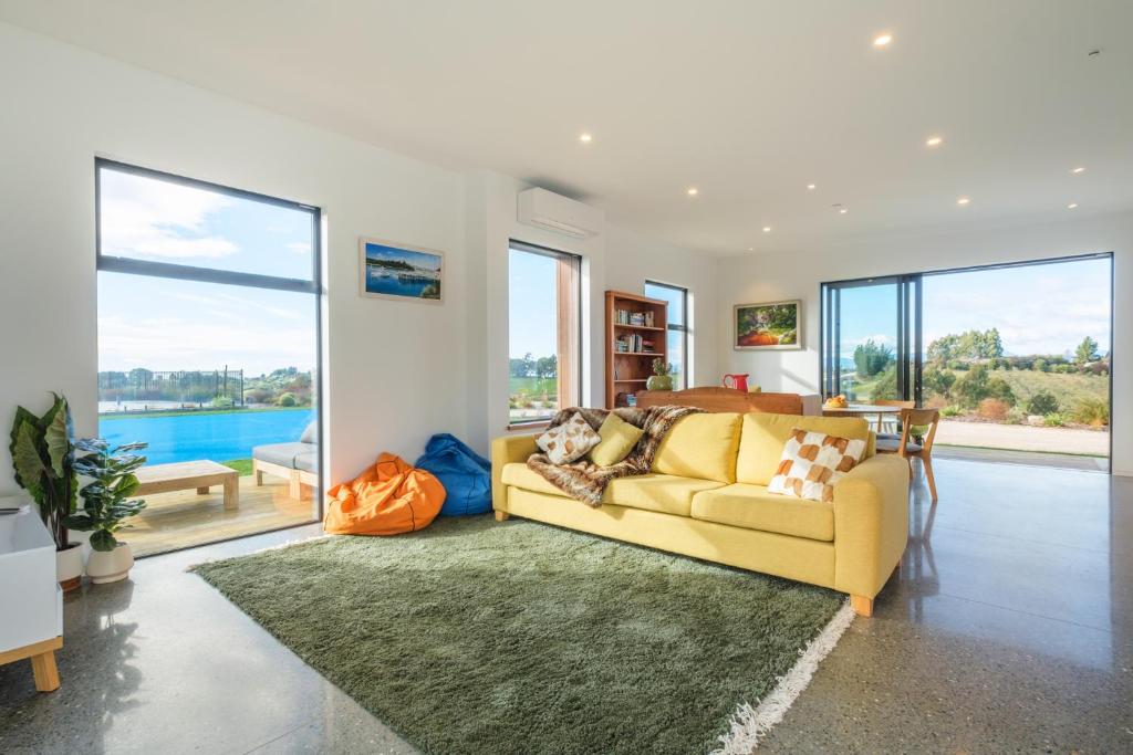 a living room with a yellow couch and large windows at Countryview Haven in Tasman