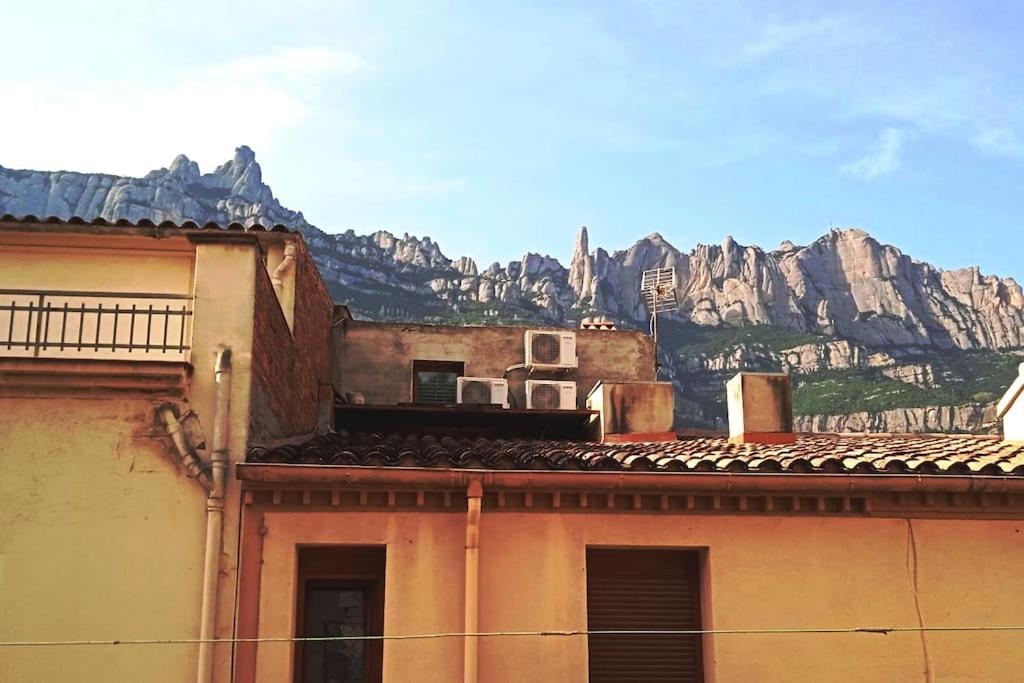 ein altes Gebäude mit einem Berg im Hintergrund in der Unterkunft piso con desayuno incluido y vistas a la montaña. in Monistrol de Montserrat