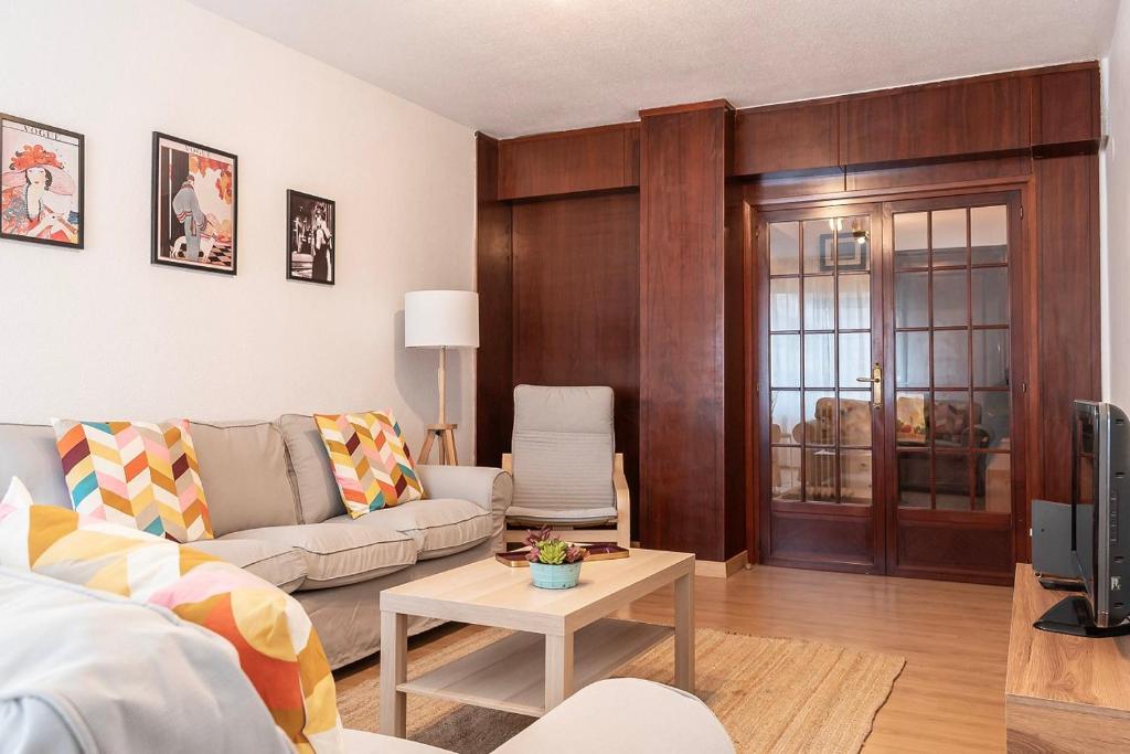 ein Wohnzimmer mit einem Sofa und einem Tisch in der Unterkunft Funcional y renovado apartamento en Iturrama in Pamplona