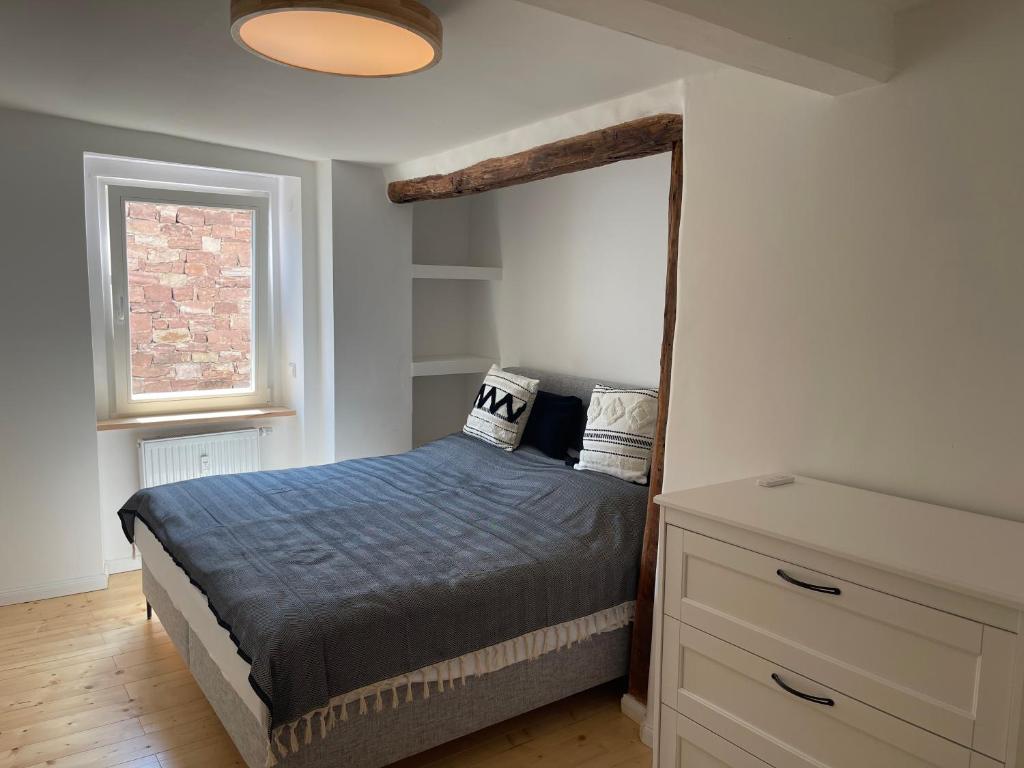 a bedroom with a bed and a dresser and a window at Tiny GetAway in Eberbach im Odenwald bei Heidelberg in Eberbach